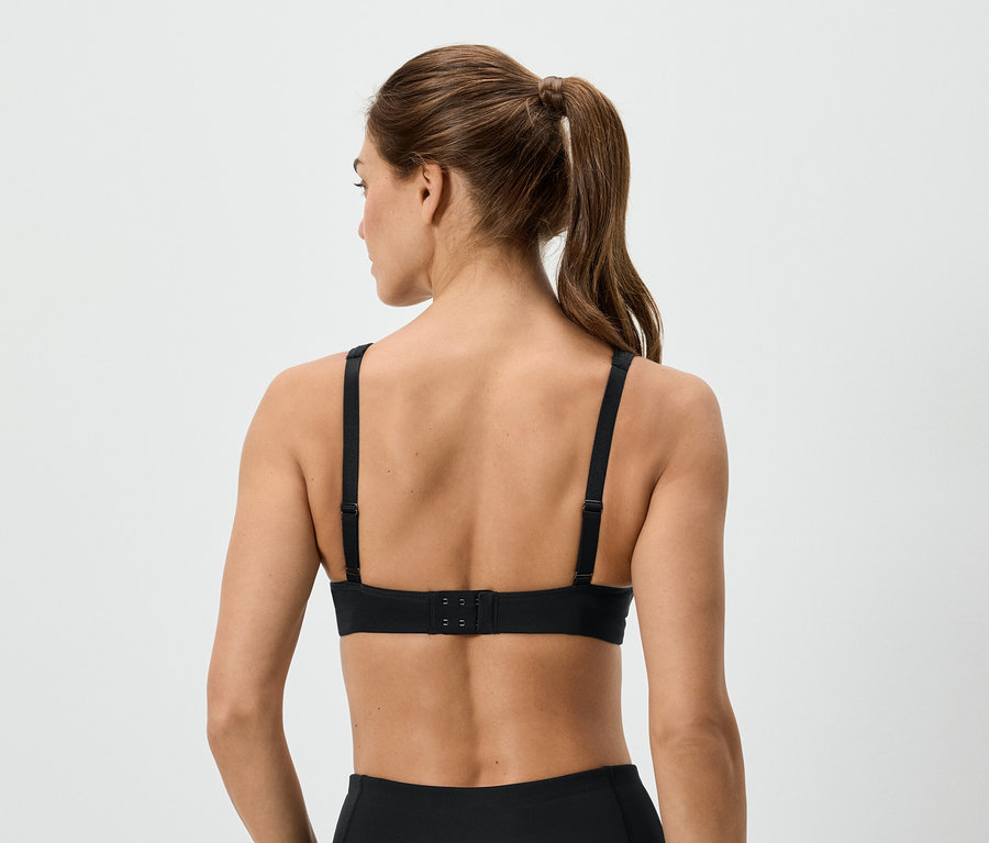 Vue arrière d'une femme avec une queue de cheval portant un soutien-gorge de sport noir.