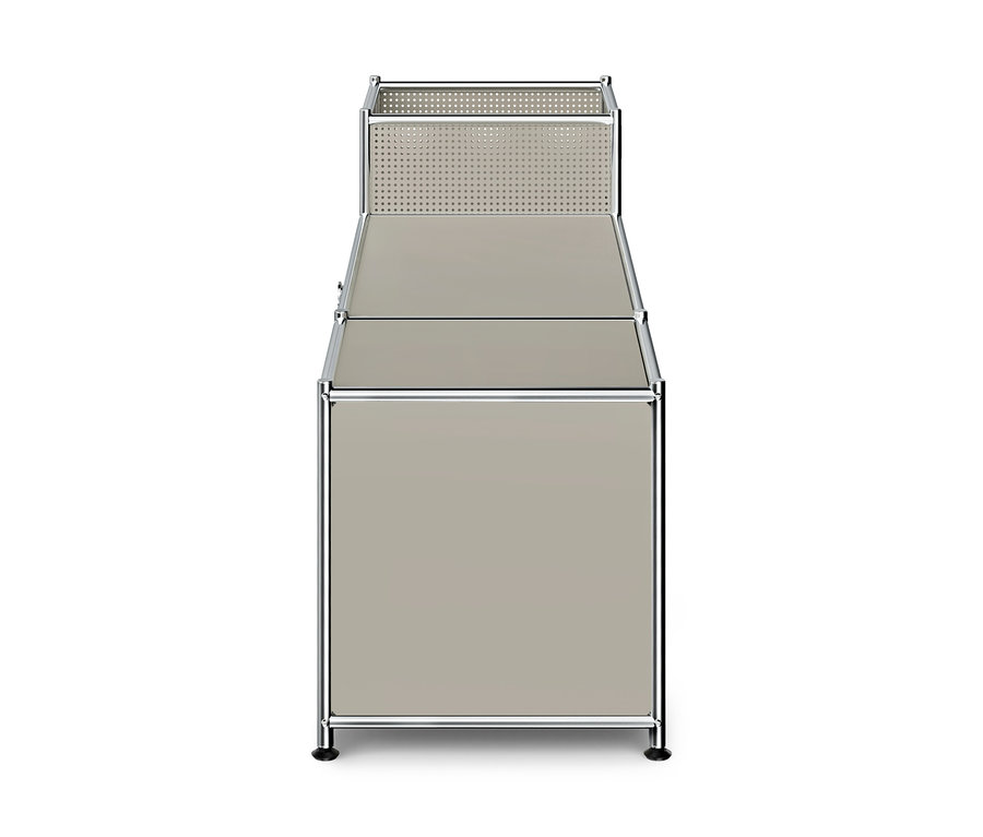 Unité de rangement modulaire avec cadre chromé et panneaux beige/gris. La section supérieure est un panier ouvert perforé. En dessous se trouve une surface plane, et la section inférieure est une armoire fermée.