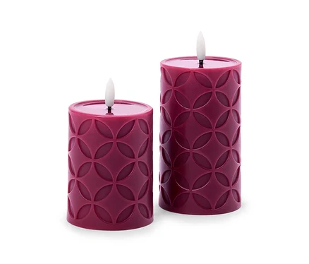 Deux bougies LED cylindriques rouge foncé avec un motif circulaire en relief, l'une plus haute que l'autre, sont côte à côte.