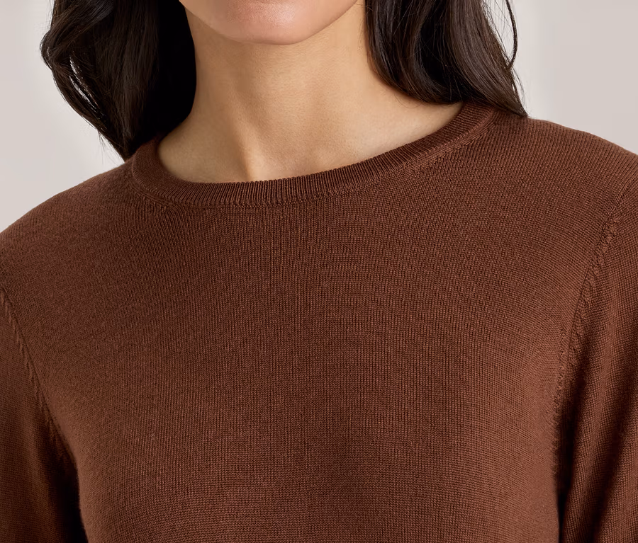 Femme portant un pull marron à manches longues et col rond.