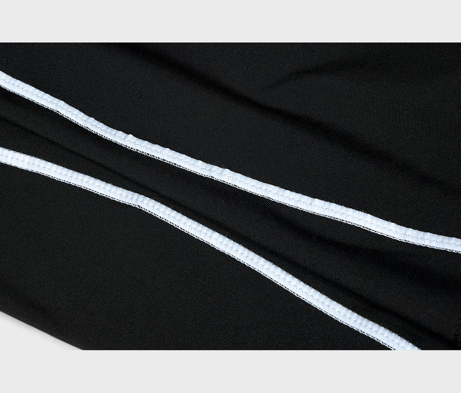 Gros plan sur un tissu noir avec deux lignes parallèles de surpiqûres blanches en diagonale.
