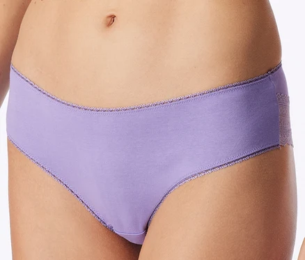 Gros plan sur le ventre d'une personne portant une culotte violet clair avec des bordures en dentelle à la taille et aux ouvertures des jambes, et un empiècement en dentelle sur le côté.