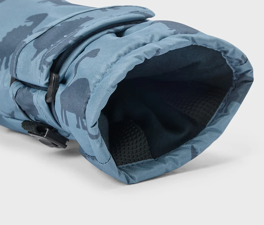 Gant bleu avec un motif de dinosaures foncés, une sangle ajustable avec une boucle noire et une doublure intérieure sombre et texturée.