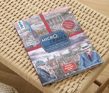 Le livre « Micro Crimes – das Krimi-Suchbuch » est posé sur un tabouret en osier.