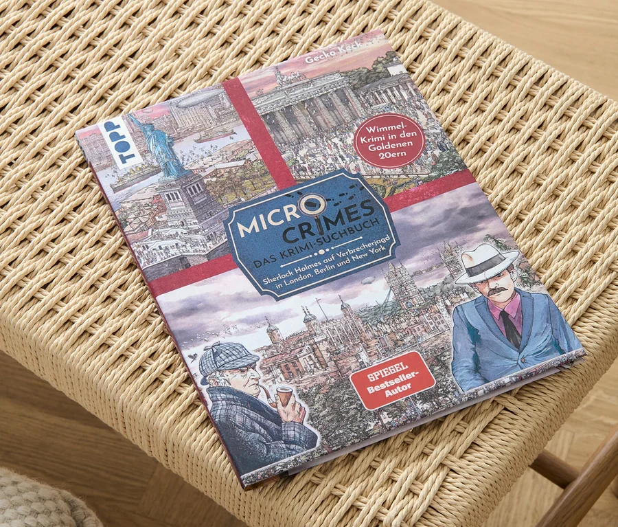 Le livre « Micro Crimes – das Krimi-Suchbuch » est posé sur un tabouret en osier.