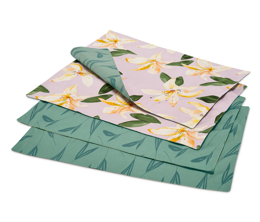 Un ensemble de 4 sets de table réversibles, dont un avec un motif floral sur fond lilas et un avec un motif de feuilles vertes.