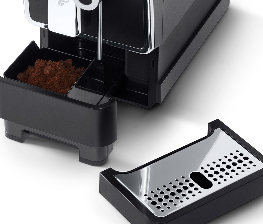 Gros plan sur une machine à café entièrement automatique de Tchibo « Esperto Pro » anthracite avec le récipient à marc de café et le bac d'égouttement retirés.
