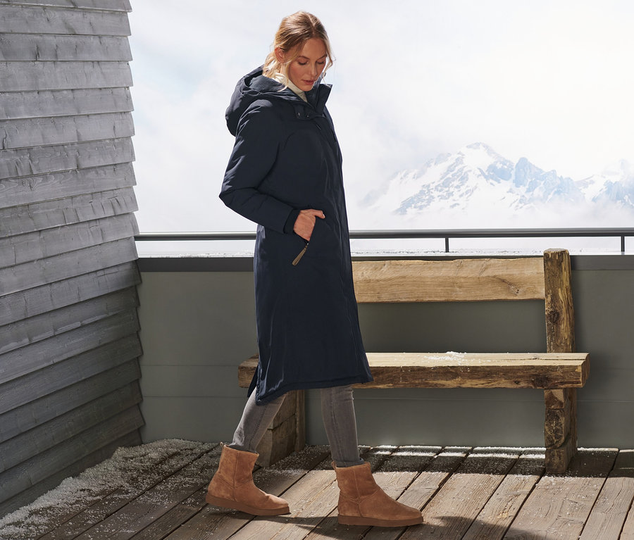 Une femme marche et porte un manteau thermique très long.