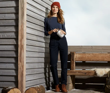 Femme tenant une thermos, portant un bonnet et un pantalon thermique.