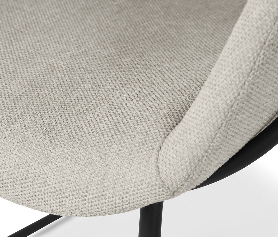 Gros plan d'une chaise coque rembourrée beige avec des pieds en métal.