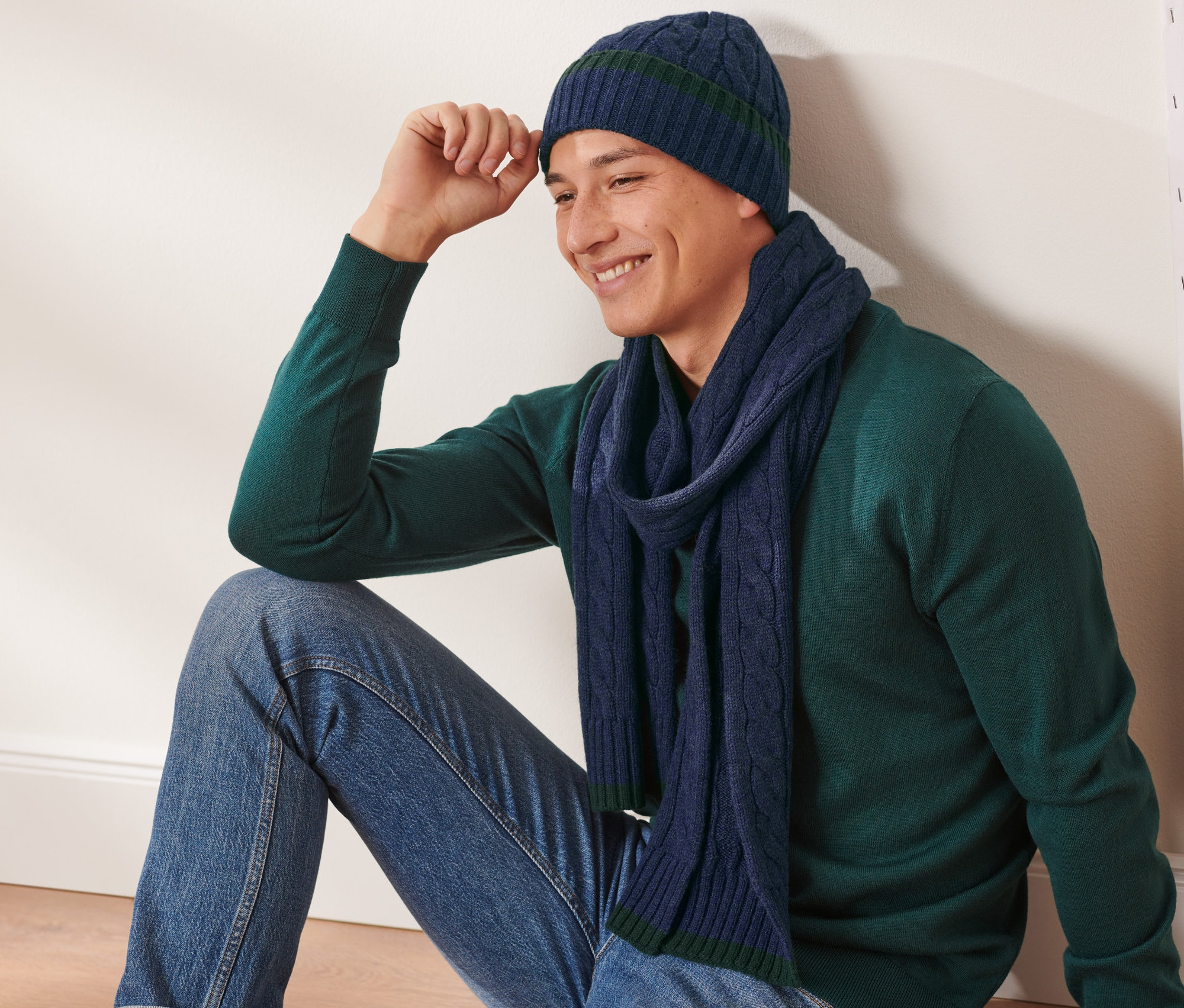 Un homme est assis et porte un ensemble bonnet et écharpe.