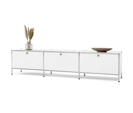 Meuble bas en métal blanc « CN3 » à 3 abattants. Un vase avec de l'herbe et un bol marron sont posés sur le meuble.