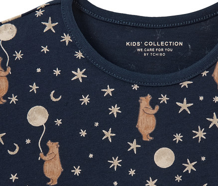 Gros plan sur un pyjama pour enfant avec des motifs d'ours, d'étoiles et de lunes imprimés sur un fond bleu foncé.