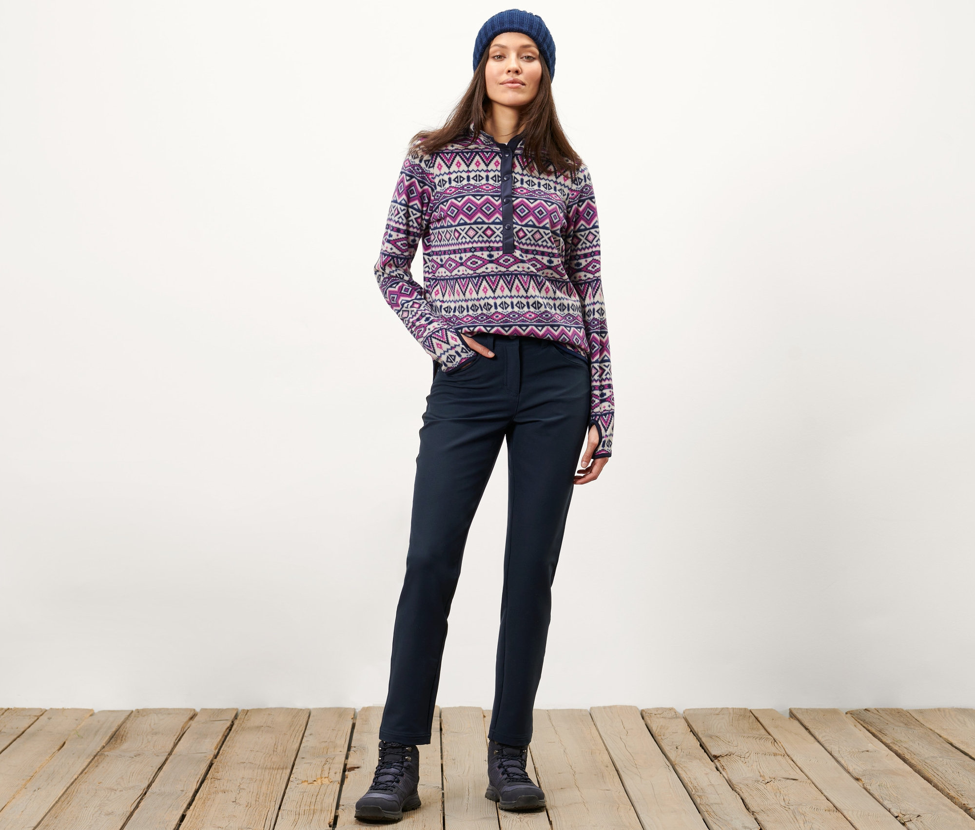 Femme posant en pantalon thermique, pull à motifs et bonnet.