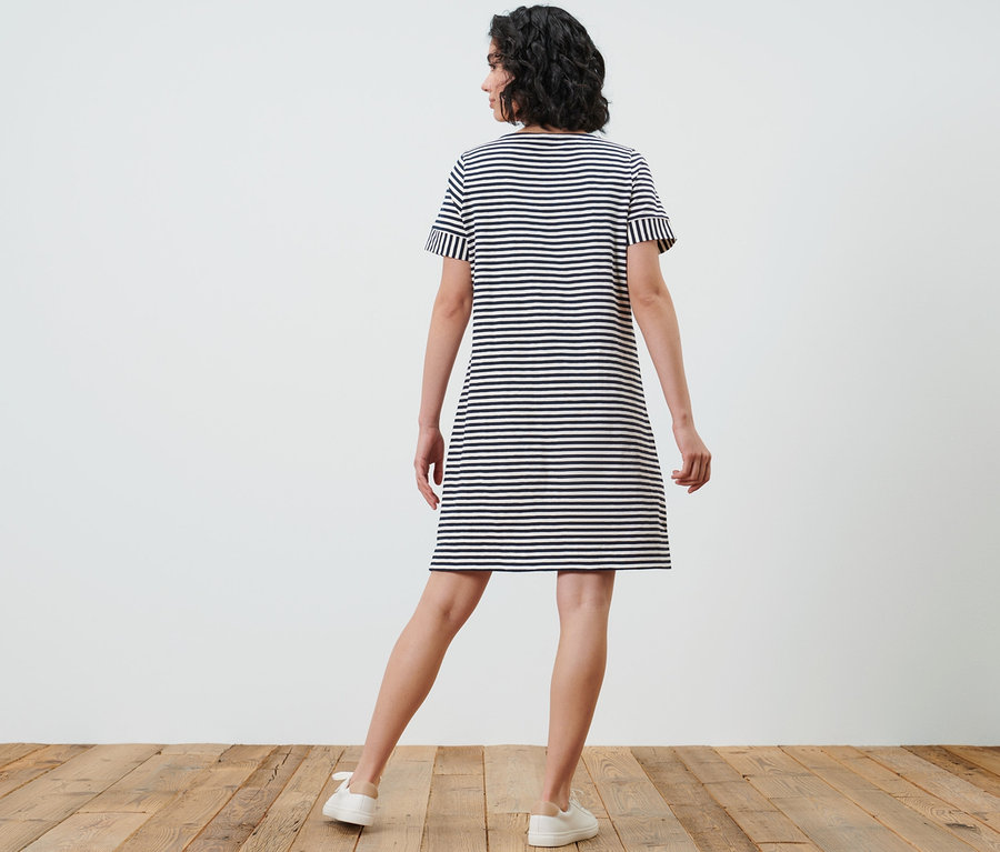 Une femme, vue de dos, porte une robe rayée en jersey.