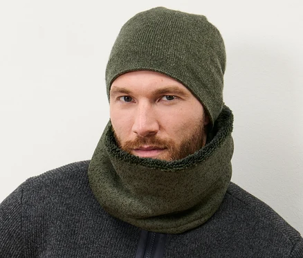 Un homme portant une écharpe-tube en polaire tricotée kaki et un bonnet tricoté assorti.