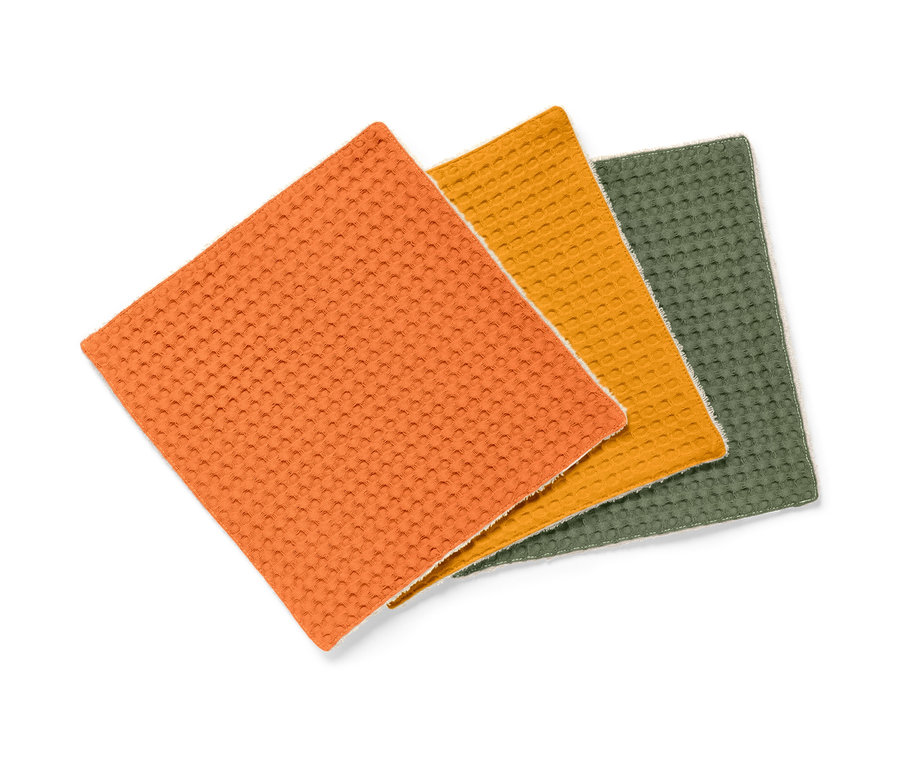 Trois lavettes absorbantes orange, jaune et verte.