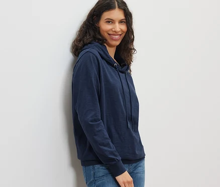 Femme souriante posant en sweat en jersey bleu marine et jean.