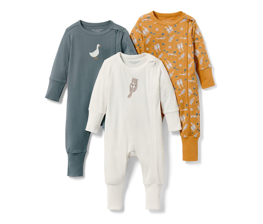 Trois pyjamas pour bébé : un bleu-gris avec une oie, un blanc avec une loutre et un moutarde avec motif loutre.