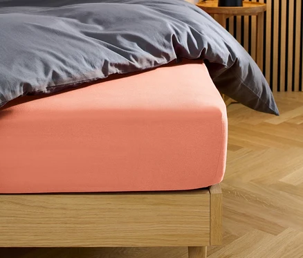 Lit avec drap-housse en jersey corail.