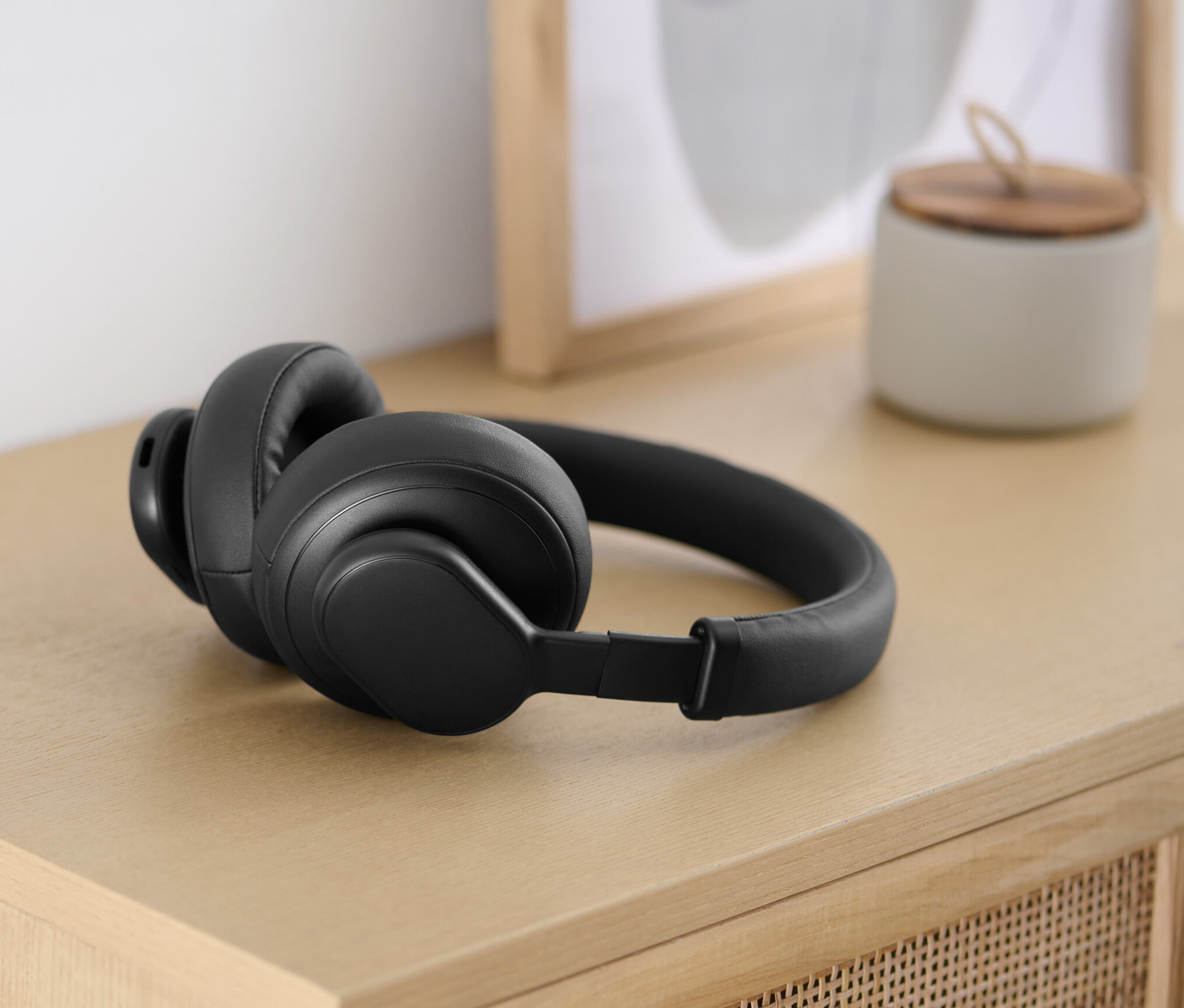 Un casque Bluetooth® noir avec fonction tactile est posé sur une table en bois clair.