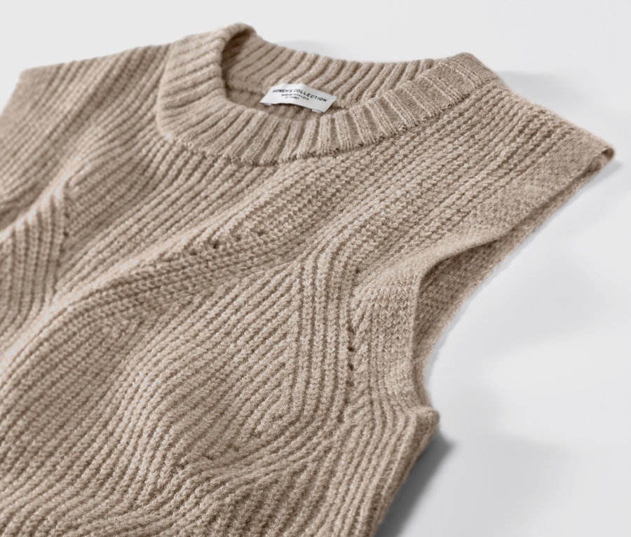 Vue détaillée d'un pull sans manches en maille beige chiné.