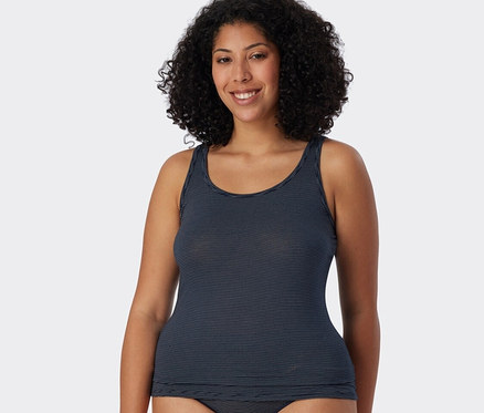 Une femme porte un débardeur bleu marine rayé de la marque SCHIESSER.