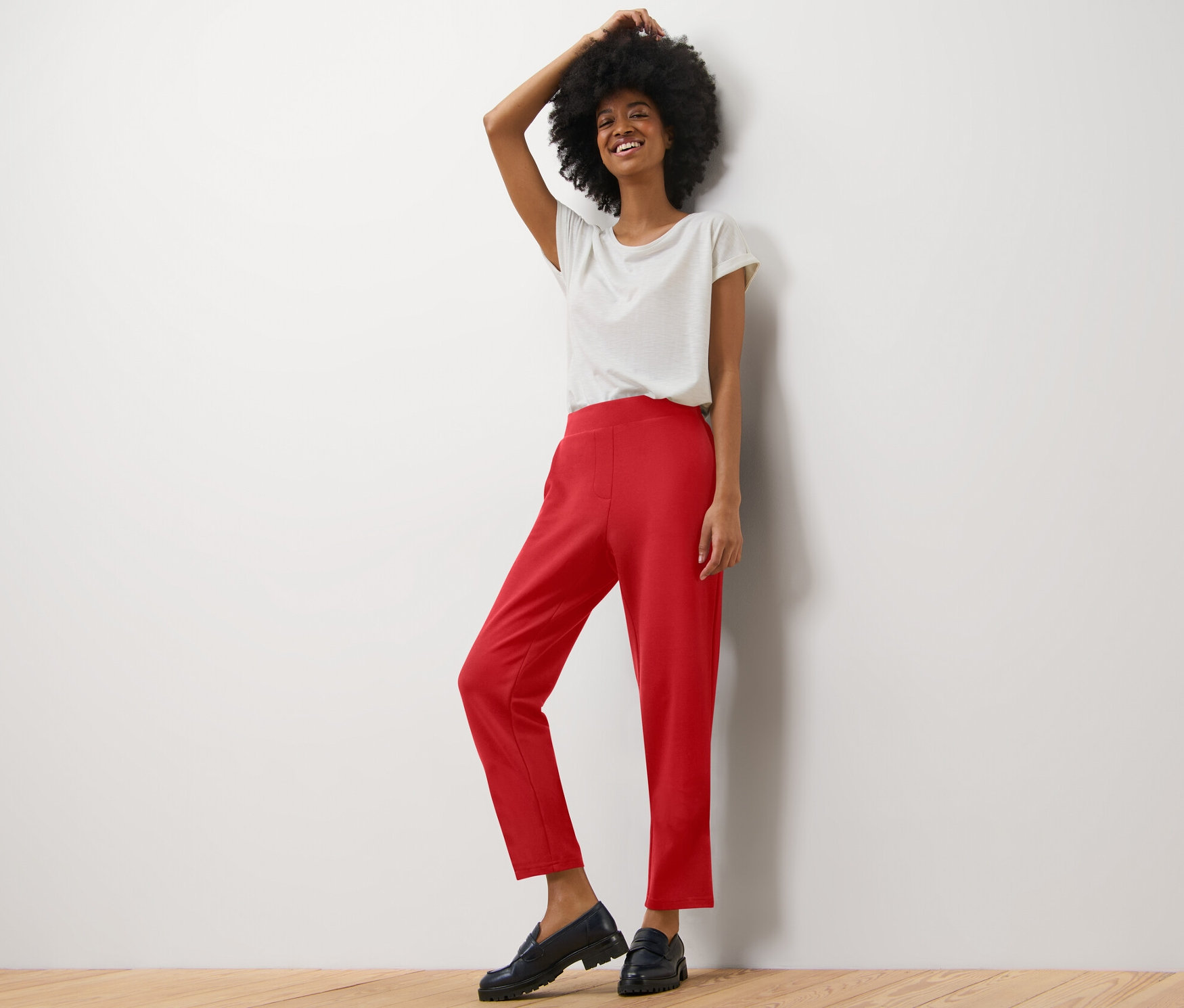 Femme posant dans un t-shirt clair et un pantalon de jogging rouge.