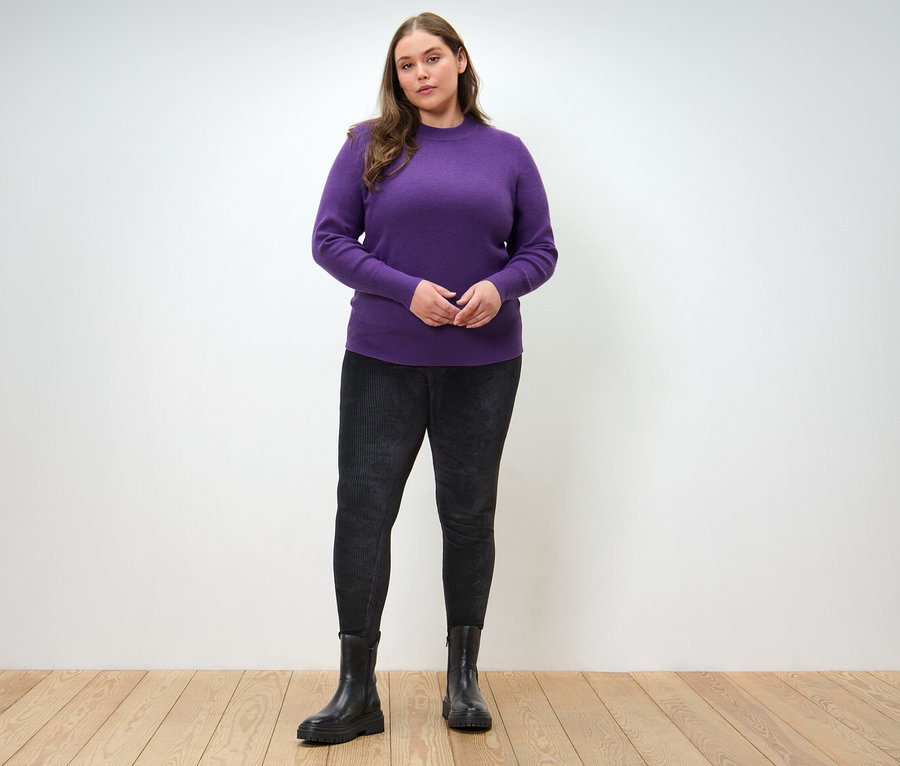 Femme posant en pull en maille fine et legging en velours côtelé.