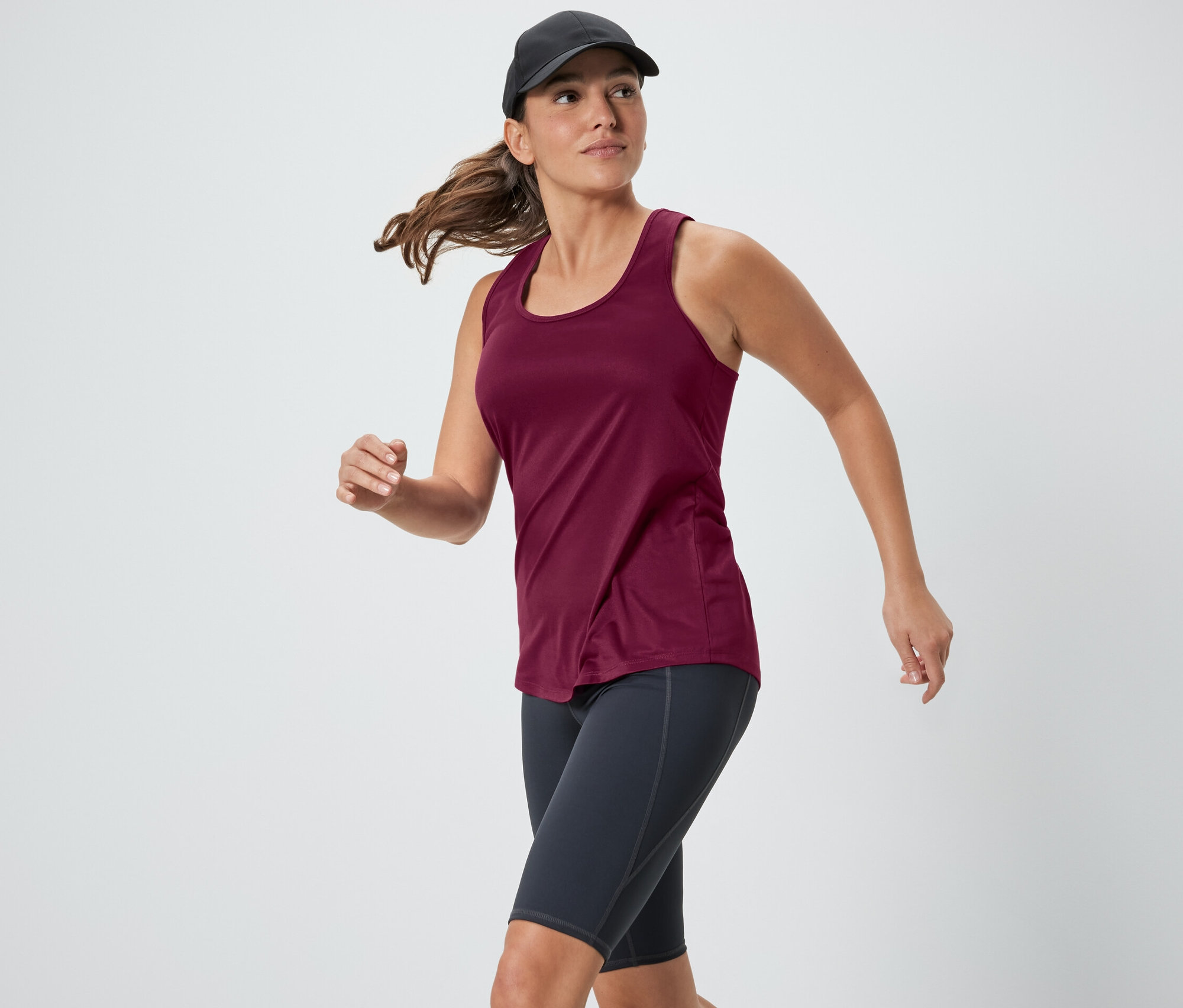 Femme courant dans un top technique rose d'un ensemble deux pièces.