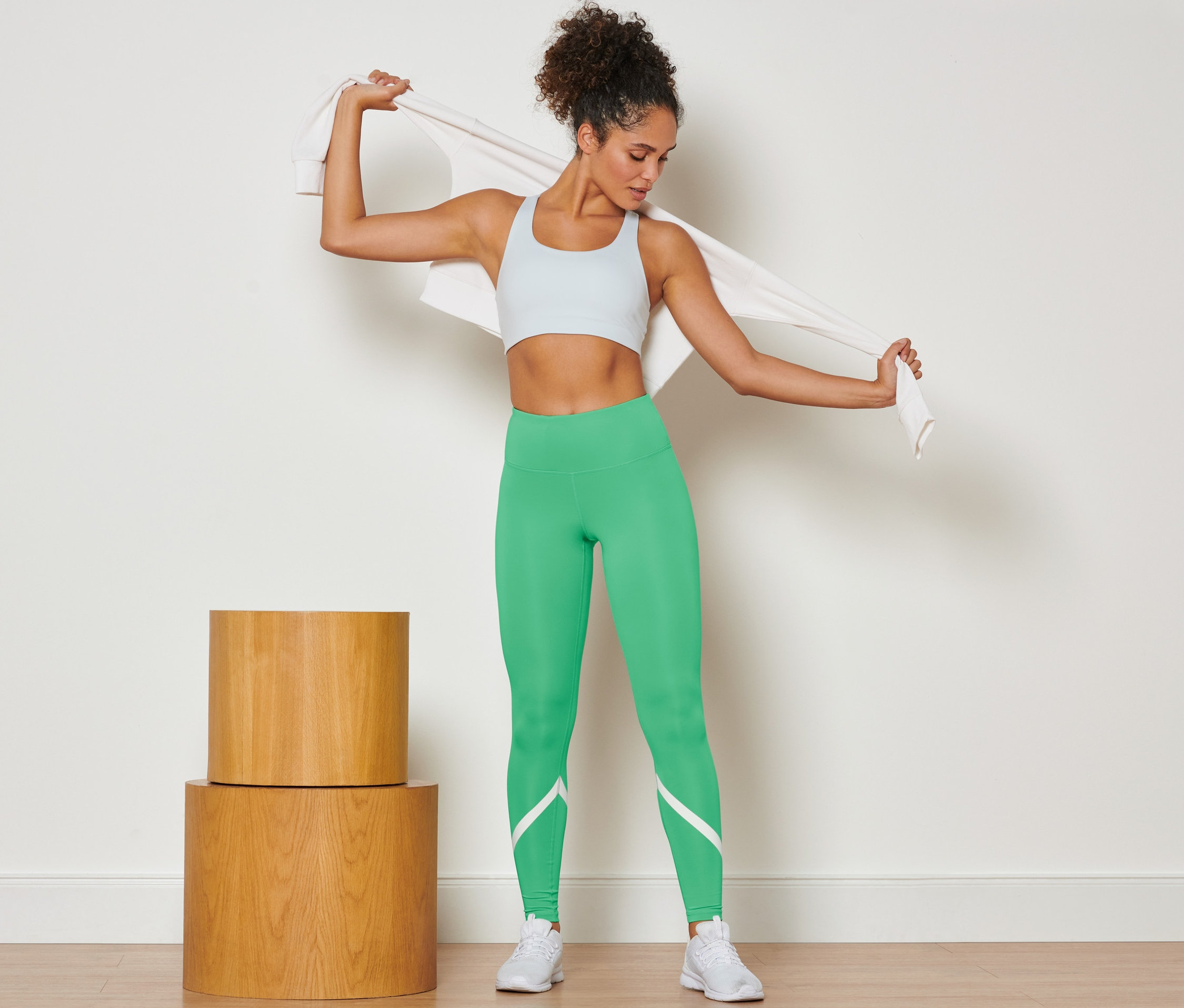 Femme drapant une serviette sur ses épaules et portant un legging de sport vert.