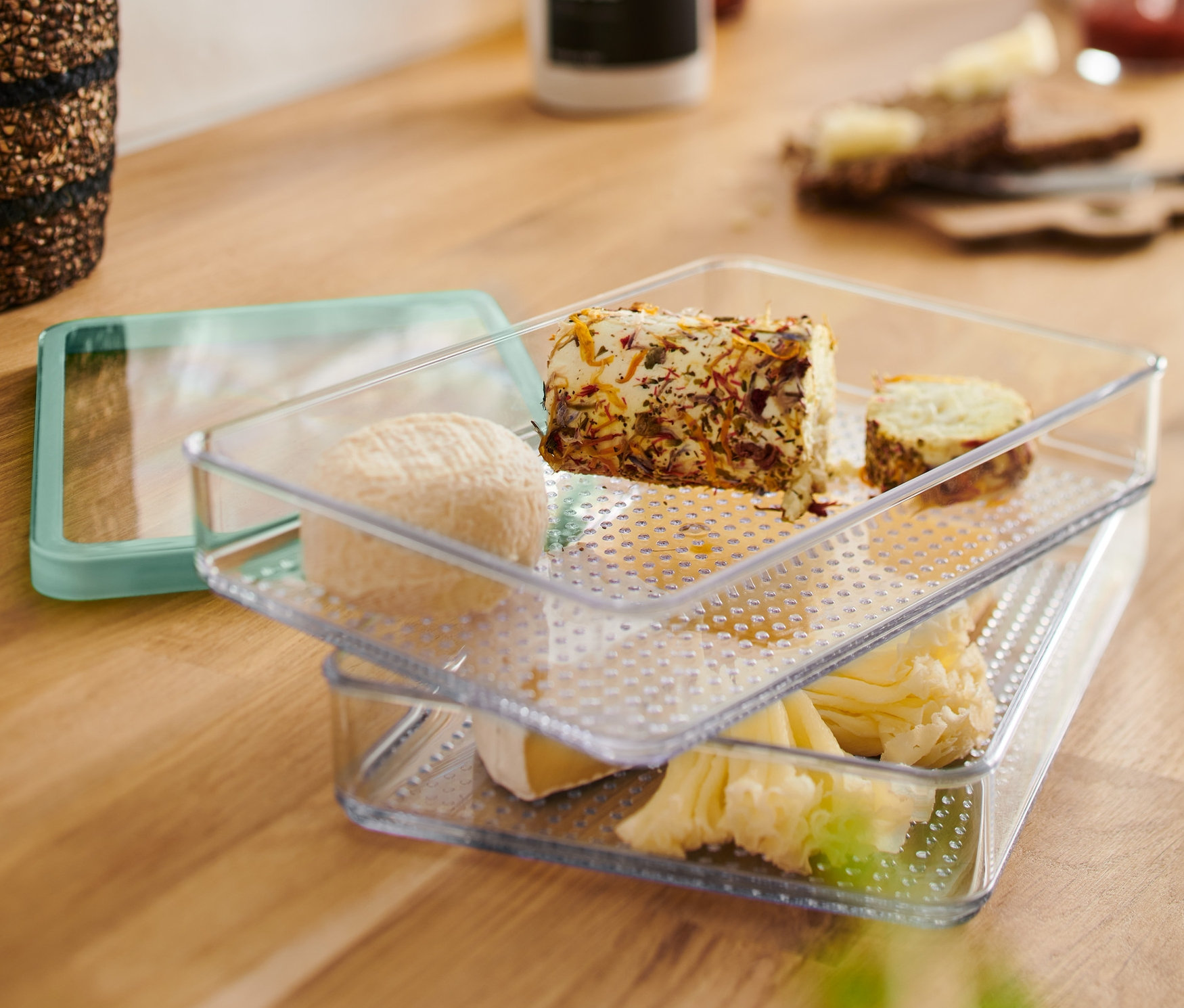 Deux Boîtes à charcuterie transparentes sont empilées l'une sur l'autre et remplies de différents fromages.