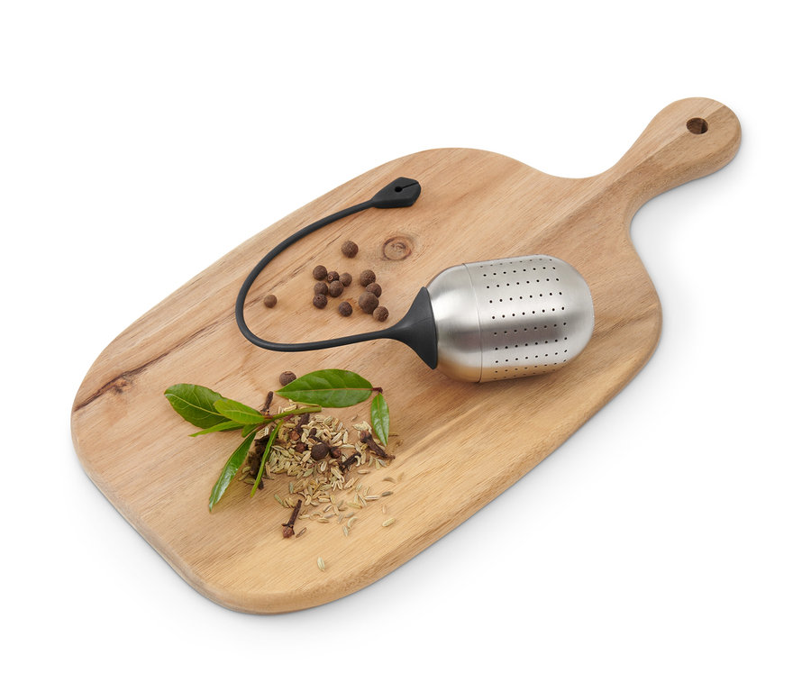 Boule à épices, épices et feuille de laurier sur une planche à découper en bois.