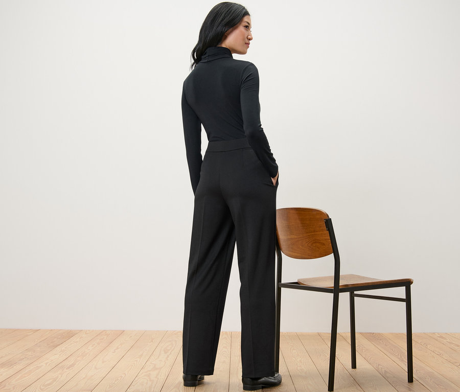 Une femme, vue de dos, porte un pantalon en jersey confortable noir.