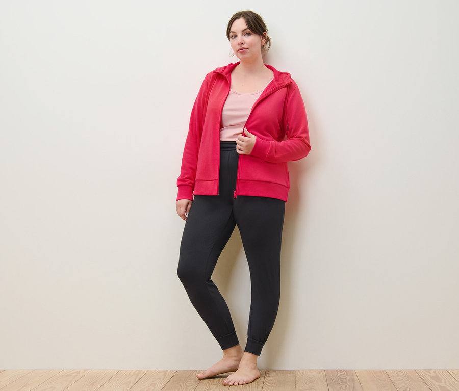 Femme posant en jaquette en sweat rose vif, pantalon de yoga et 2 tops, rose pâle/rose vif.