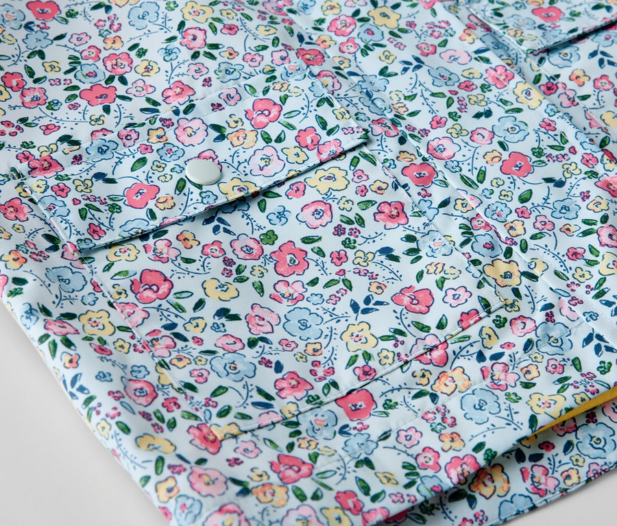 Gros plan sur une veste de pluie pour enfant à motif floral.