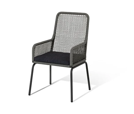 Une chaise à dossier haut en textile tressé avec un coussin d'assise gris foncé sur fond blanc.