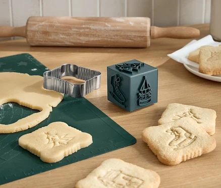 Des biscuits de Noël sont découpés à l'aide d'un emporte-pièce, d'un rouleau à pâtisserie et d'un tampon à biscuits.