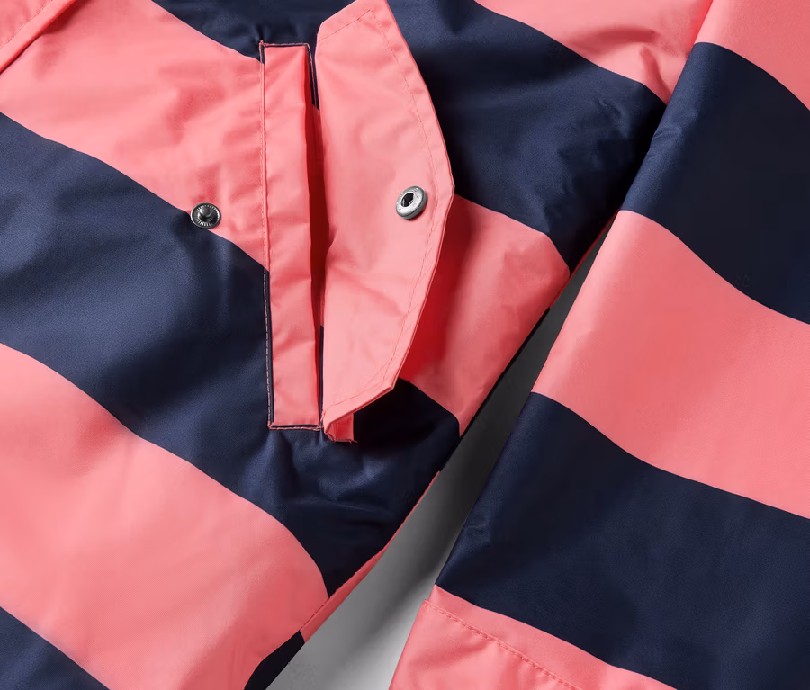 Détail d'une veste de pluie 3 en 1 à rayures roses et bleu foncé avec une poche.