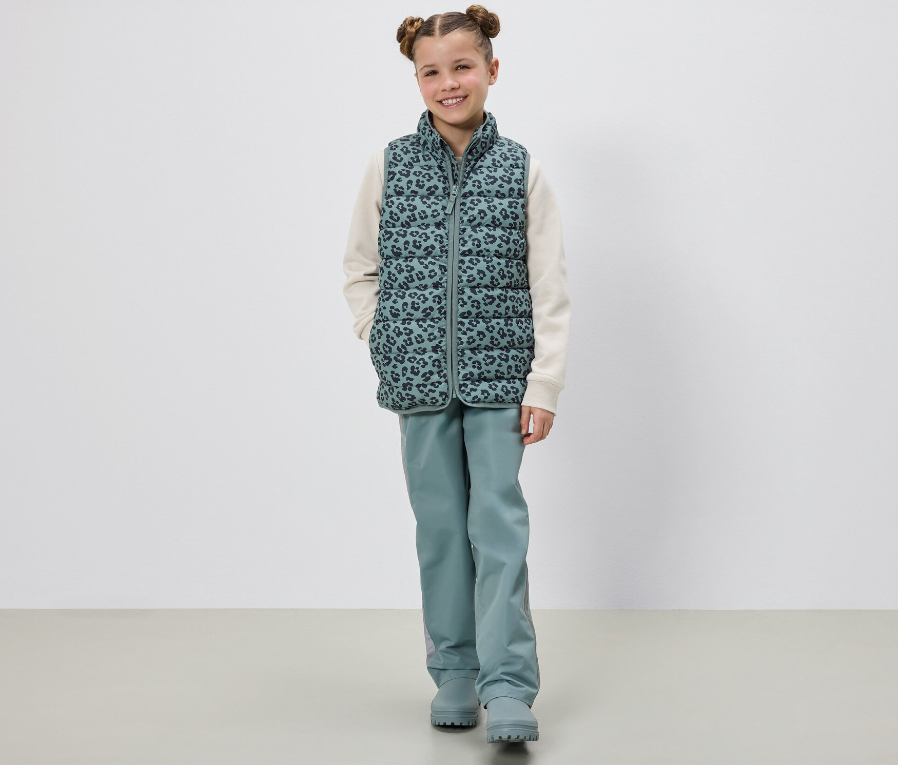 Une fille pose en doudoune sans manches pour enfants.