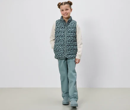 Une fille pose en doudoune sans manches pour enfants.