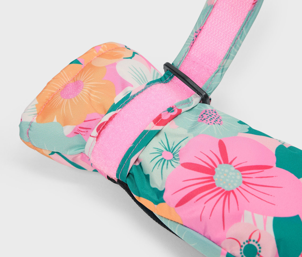 Gros plan sur un gant de ski fleuri multicolore avec une bride rose.