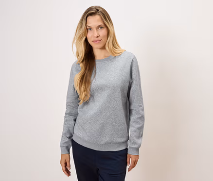 Une femme portant un pull gris et un pantalon bleu marine.
