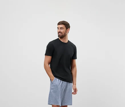 Un homme en t-shirt noir et short gris regarde vers la droite.