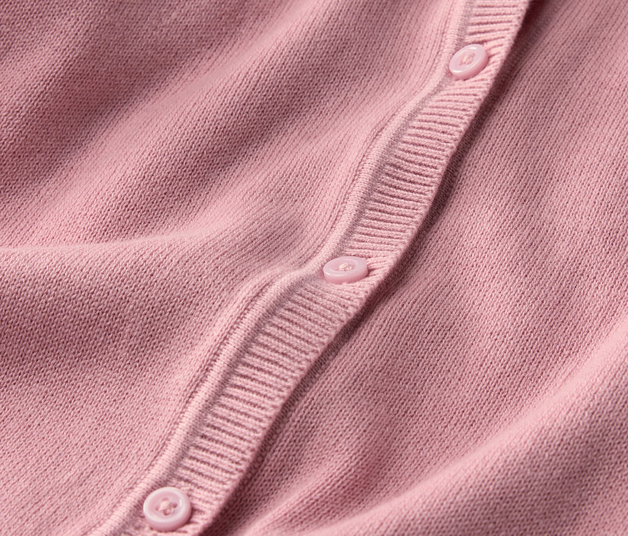 Gros plan sur une veste en maille pour enfant avec des boutons.