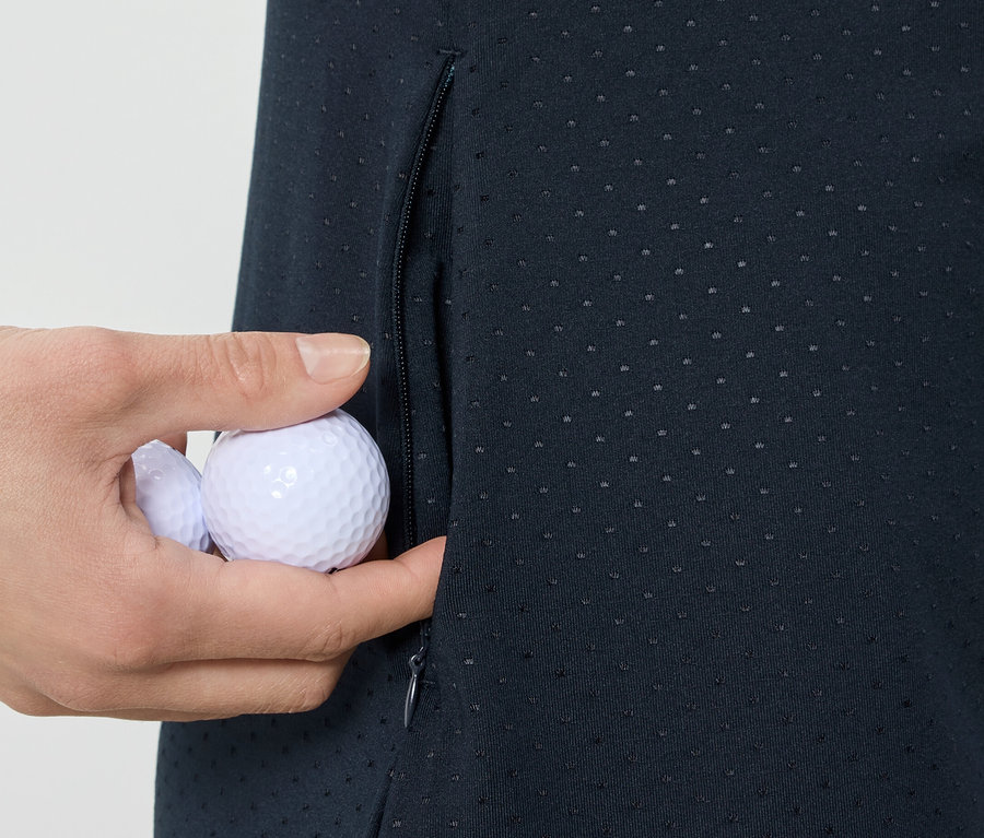 Une main place des balles de golf dans la poche d'une robe de sport.