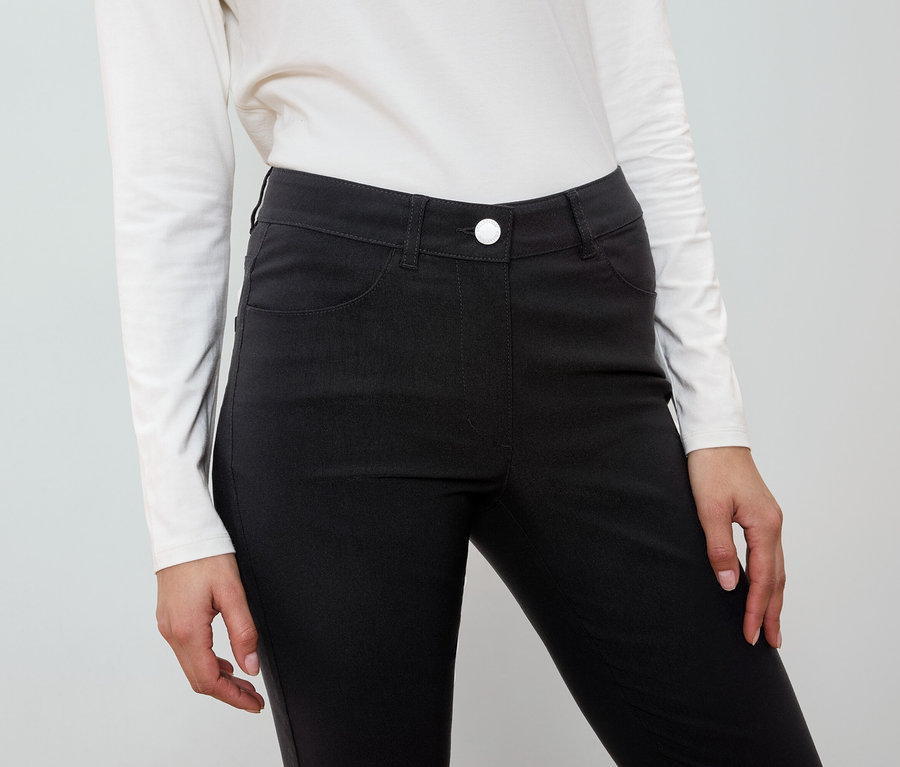 Une femme porte un pantalon noir et une chemise blanche.