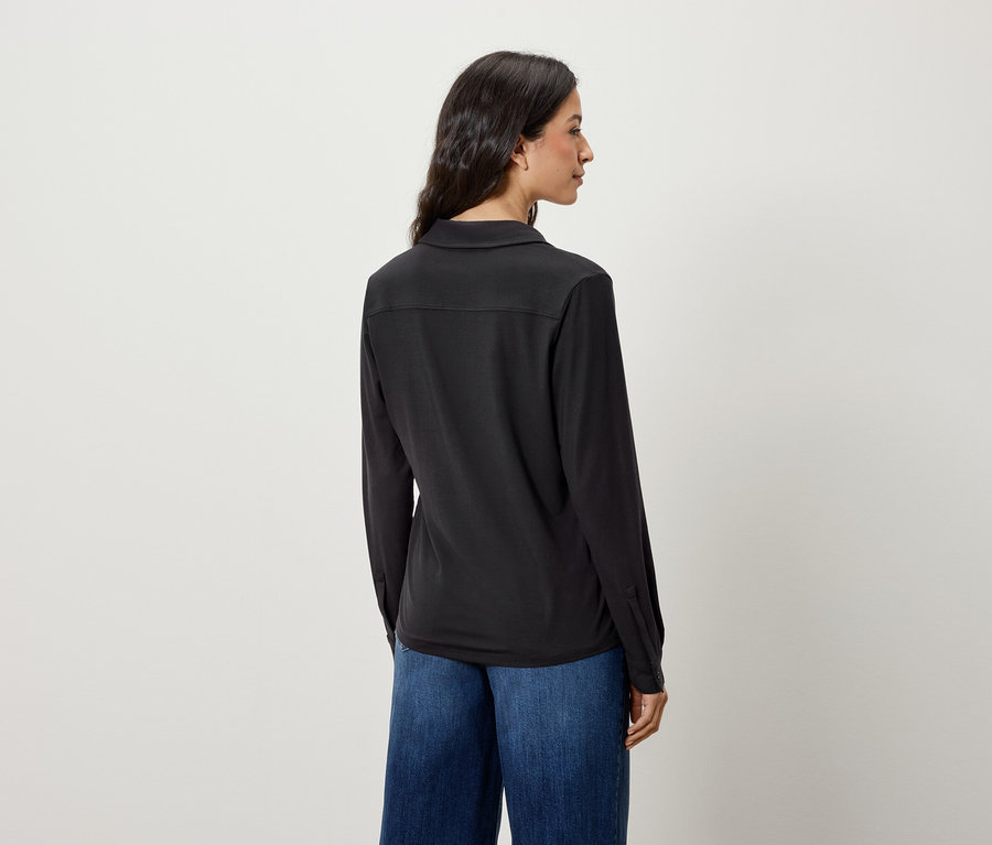 Vue arrière d'une femme aux cheveux longs portant une chemise noire à manches longues et un jean bleu.