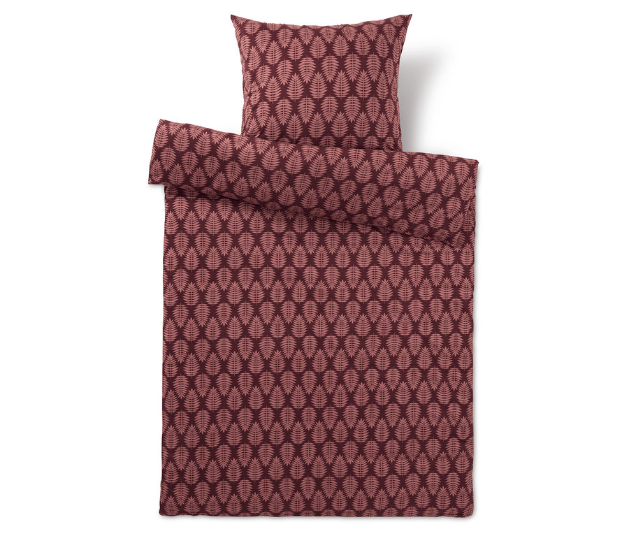 Literie bordeaux avec motif de feuilles et oreiller.