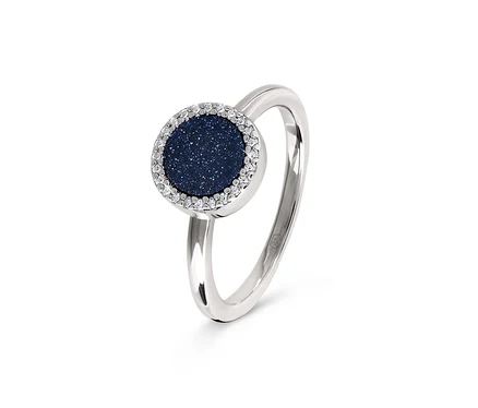 Gros plan d'une bague argentée avec une pierre ronde bleu foncé entourée de pierres transparentes.